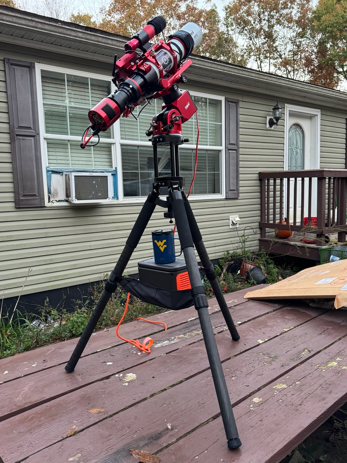 Endurance's red-and-white refractor, cooled camera, equatorial mount, and tall carbon-fiber tripod set up outdoors in daylight
